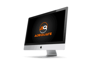 A sleek Apple iMac displaying a black screen with an orange and white circular logo and the word "ADEQUATE" written below it in bold orange capital letters. The iMac sits against a plain black background.