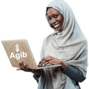 A woman wearing a light grey hijab and dark grey clothes is smiling while using a laptop. The laptop has a logo and the word "Agib" on the back. The background is light blue.